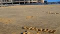 CIDADE A REVELIA - BLOCK LETTER. Texto moldado na areia da praia.
